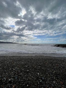 A rocky beach with dramatic clouds and crashing waves under a moody sky.