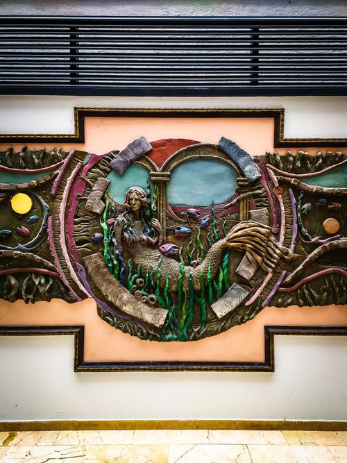 Free Colorful bas-relief of a mermaid on an ornate building wall indoors. Stock Photo