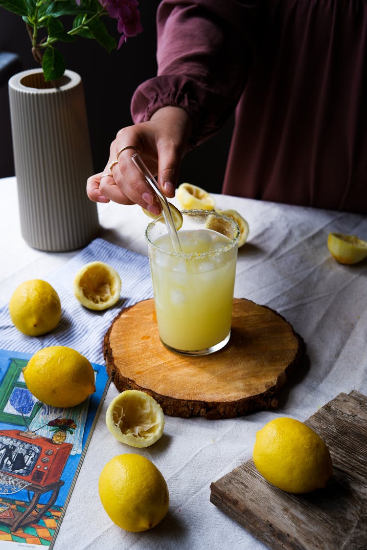 Woman Mixing A Lemonade And Used Lemons On A Table