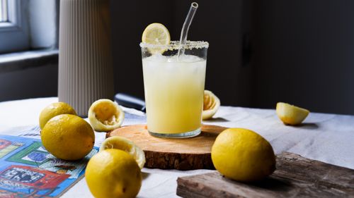 Free Freshly made lemonade in a glass with lemons on a rustic table. Perfect refreshment. Stock Photo
