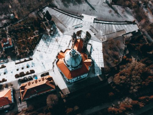 Free Drone shot capturing a historic cathedral with red roof and surrounding architecture from above. Stock Photo