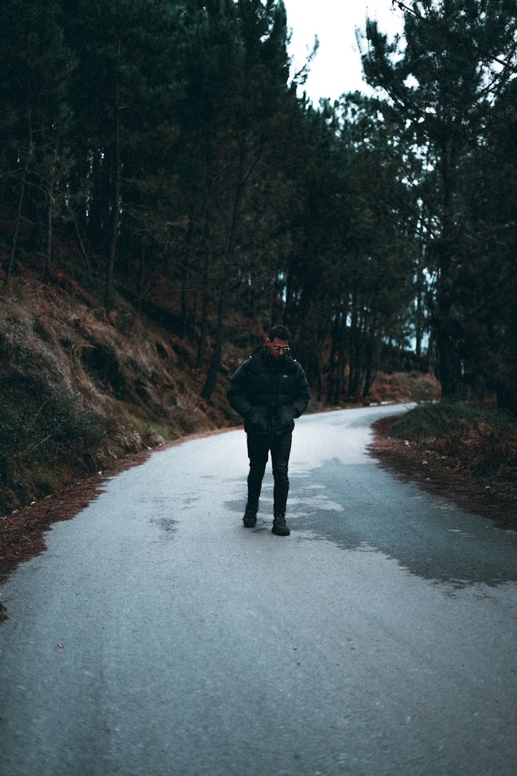 A Man In Black Jacket And Pants Walking On The Road