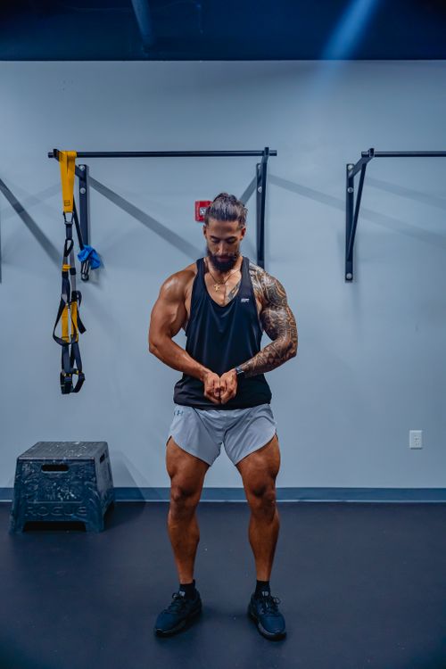 Free Tattooed bodybuilder flexing muscles in gym with gym equipment background. Stock Photo