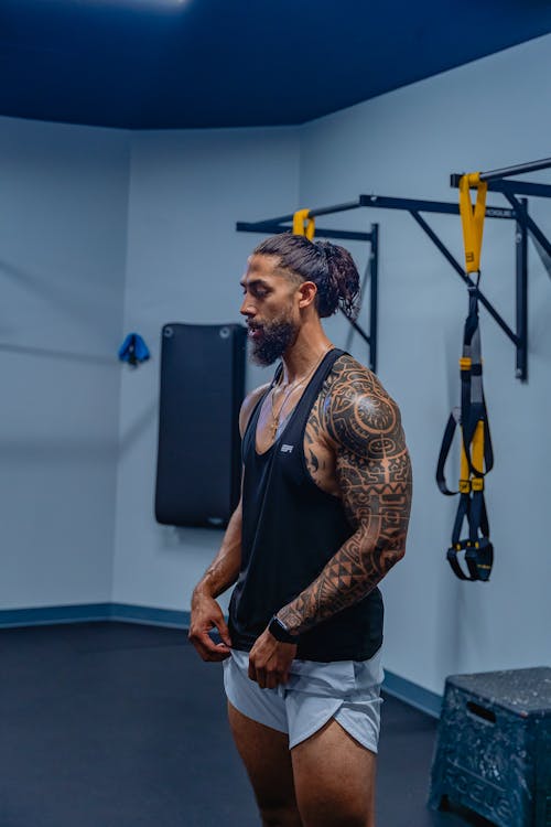 A Tattooed Man in Black Tank Top with Beard on His Face