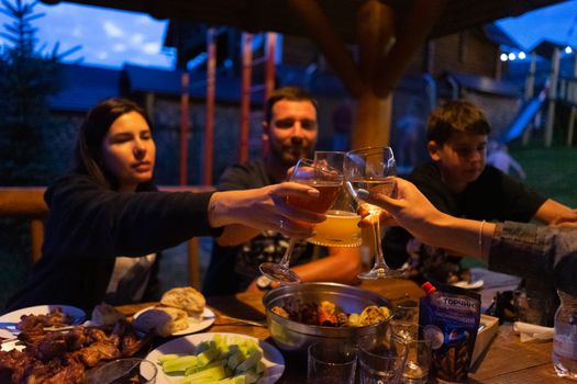 Friends clinking glasses at an outdoor dinner party, enjoying food and drinks.