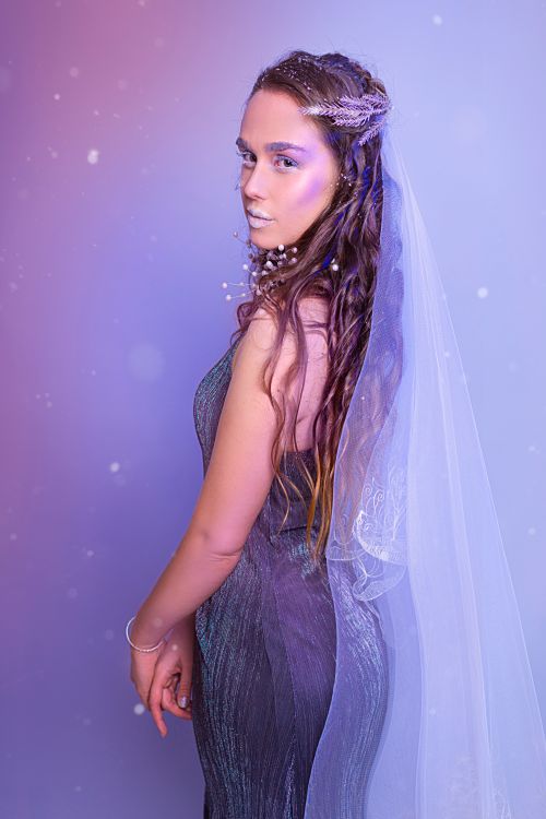 Free Captivating image of a woman in a sleeveless gray dress with a veil, looking back over her shoulder. Stock Photo