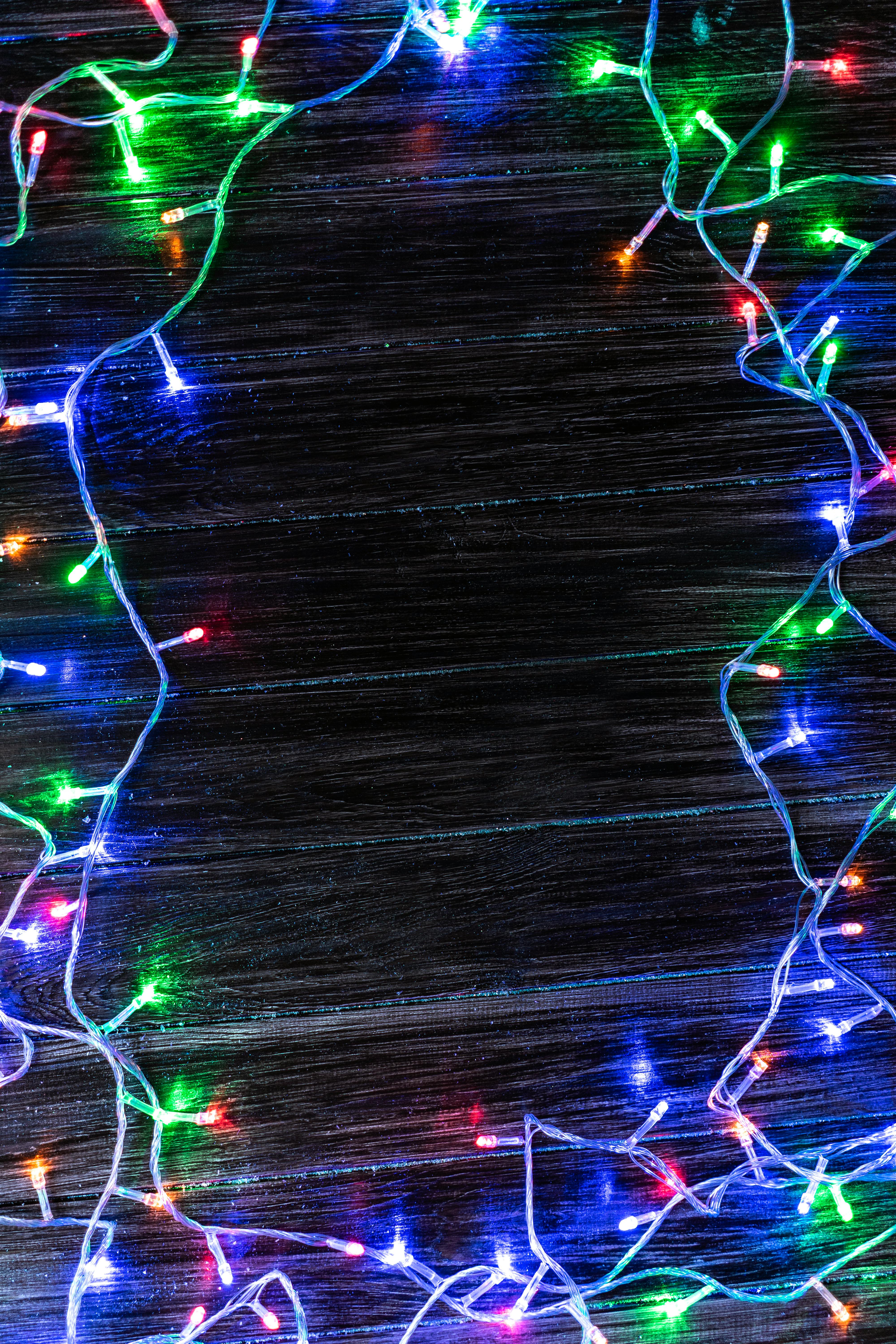 Vibrant tangled Christmas string lights on dark wood for festive designs.
