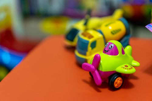 Free A vibrant toy airplane and concrete mixer on an orange table, creating a playful scene. Stock Photo