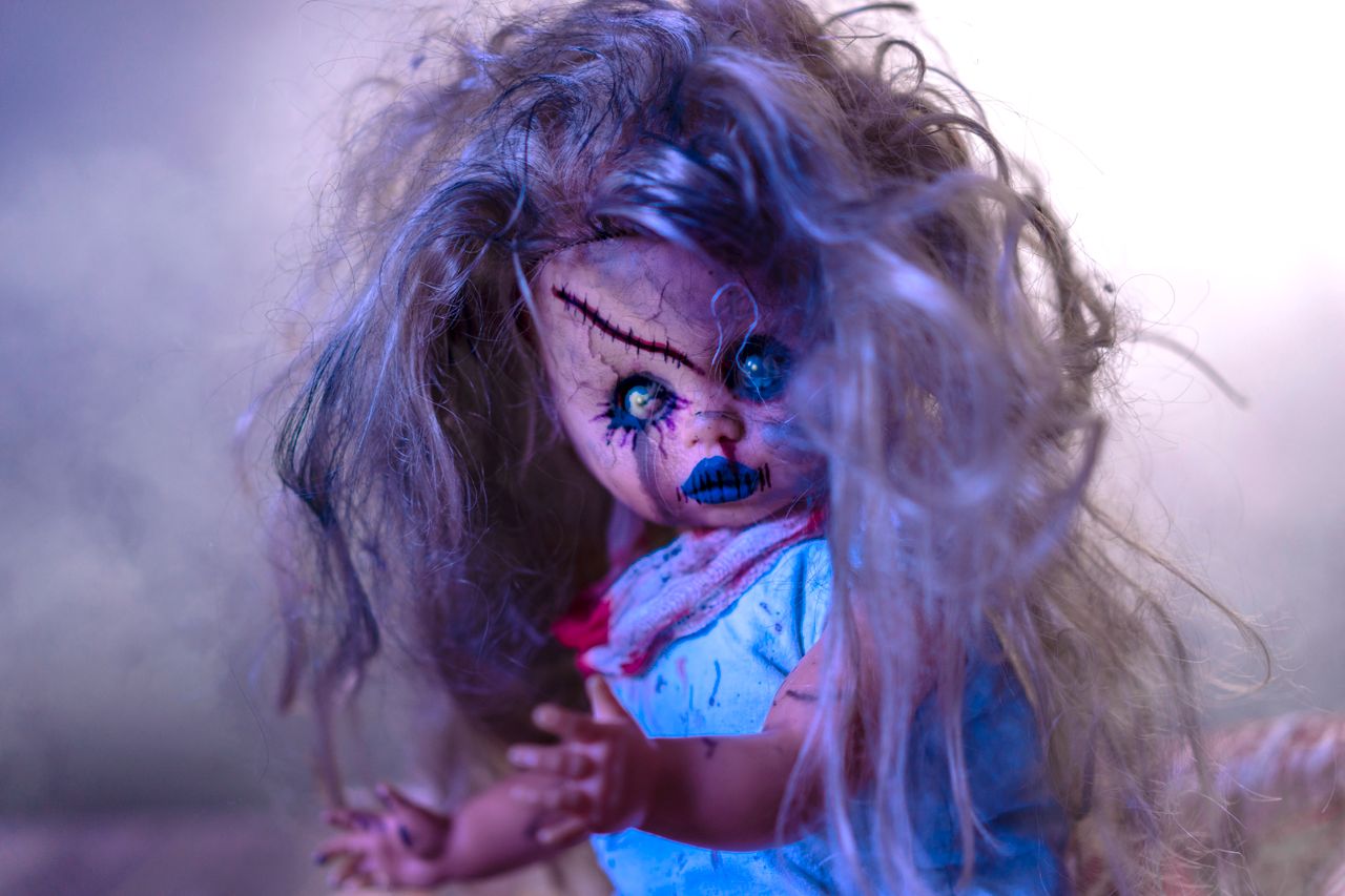 close up shot of a creepy horror doll with eerie makeup and tattered h
