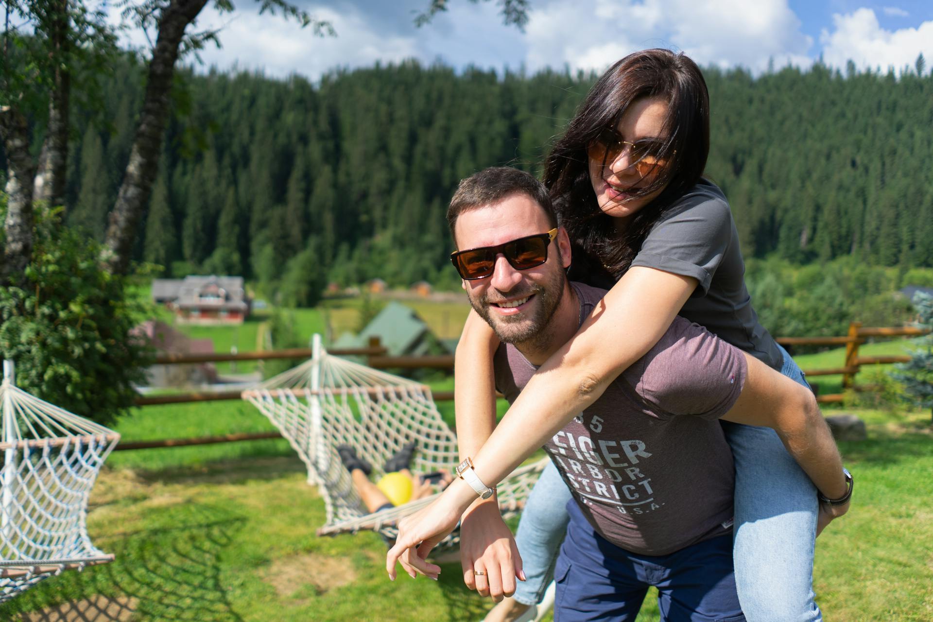 Smiling couple having fun with a piggyback ride in a scenic outdoor setting.
