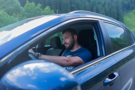 Bearded man enjoying a drive through lush green countryside on a sunny day.