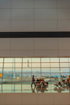 Passengers waiting in a modern airport terminal with large windows and ample seating.