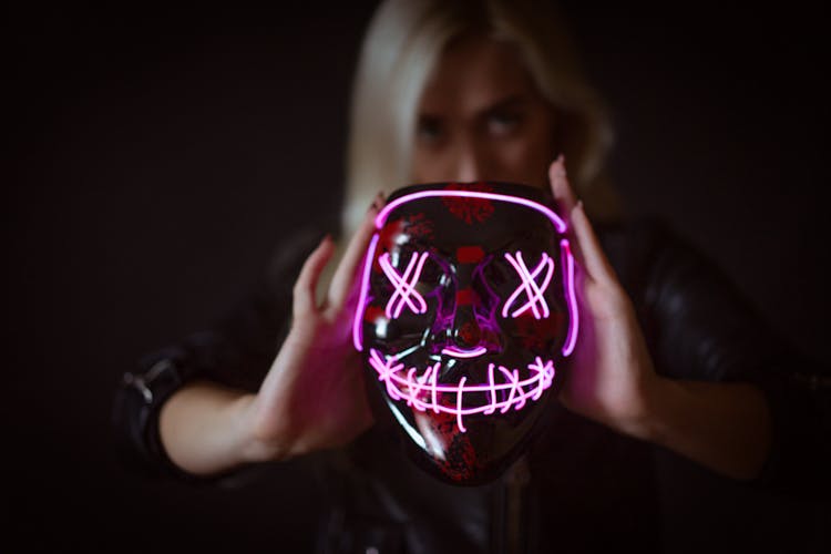 A Woman Holding A Neon Mask