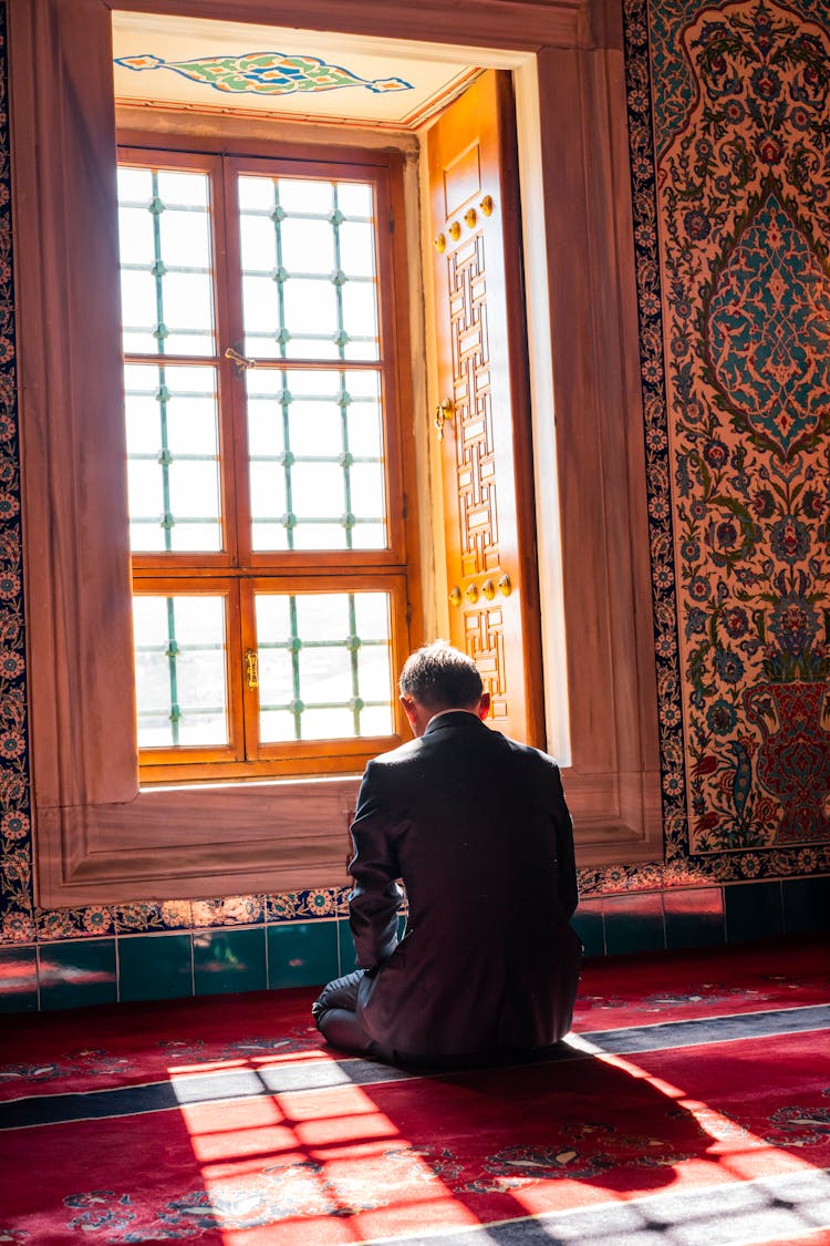 Man Kneeling And Praying By The Window