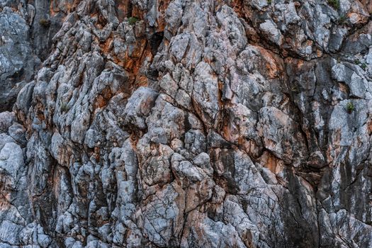 Detailed view of a rugged rocky cliff with natural textures and varied colors.