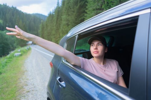 Free Young woman in a car enjoying a scenic drive in Bukovel, Ukraine, reaching out of the window. Stock Photo