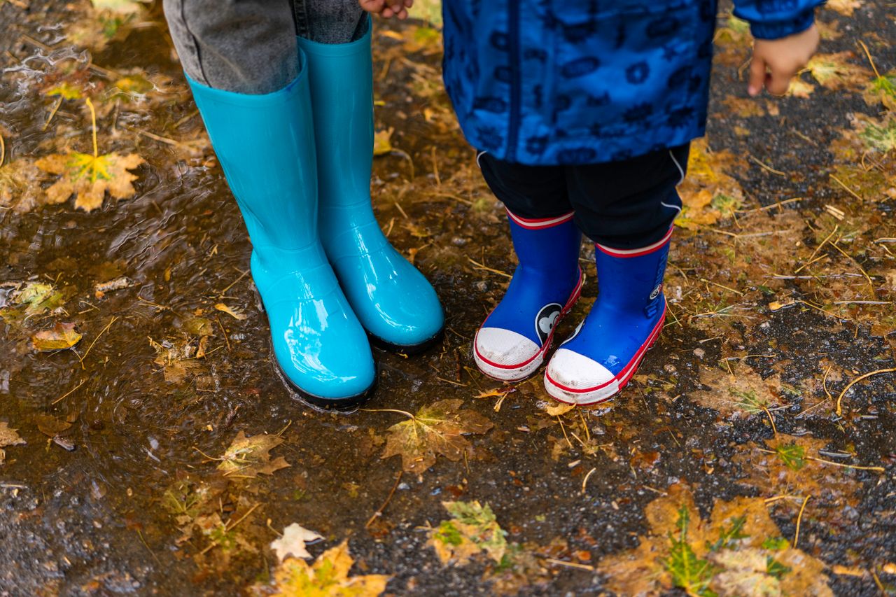 kids in bright rain boots standing in a puddle