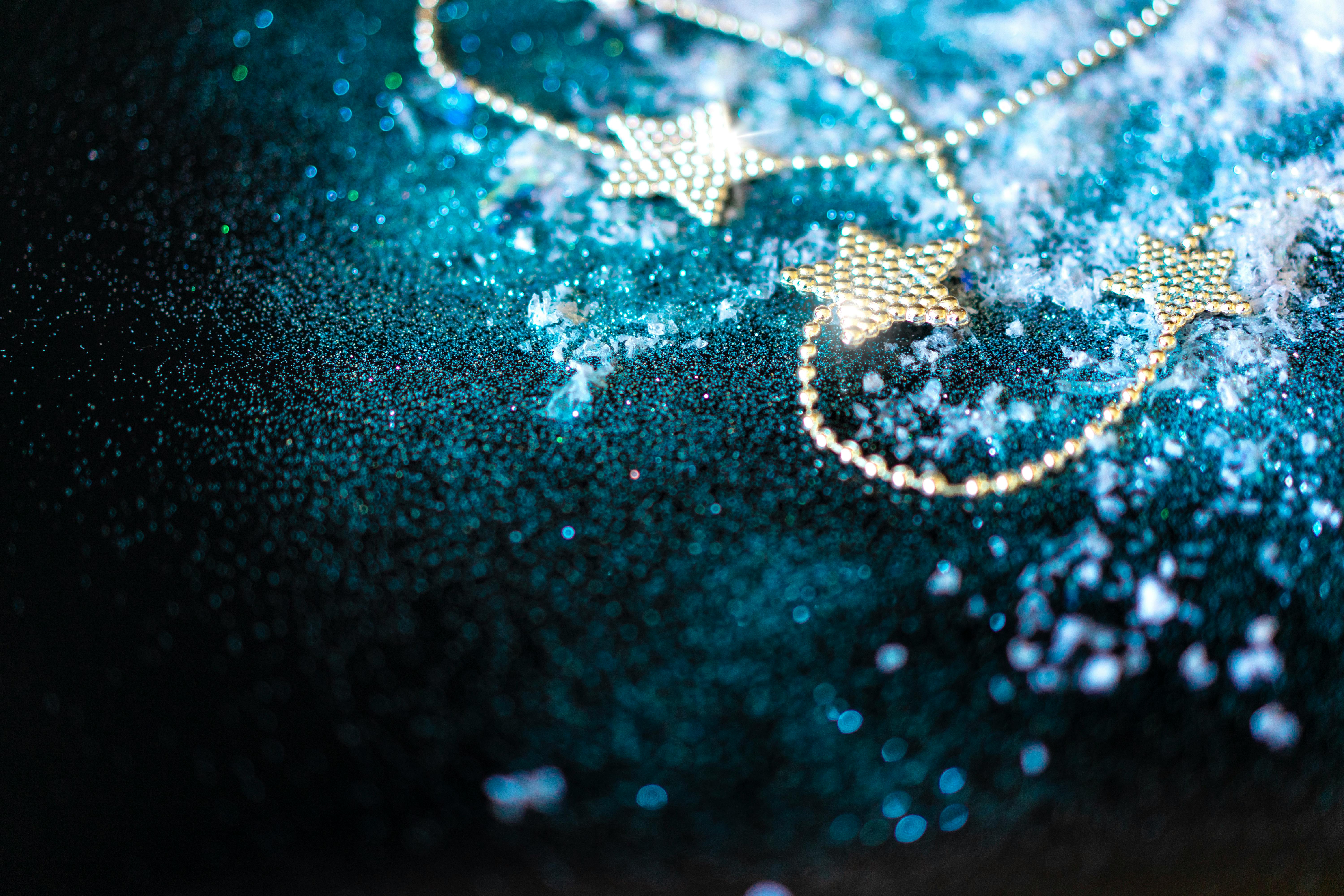Golden star garland on a shimmering blue surface with scattered snowflakes, creating a festive mood.