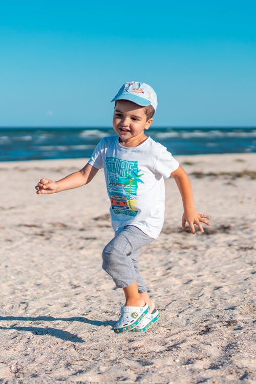 Boy in White T-shirt Running on Beach Sand
