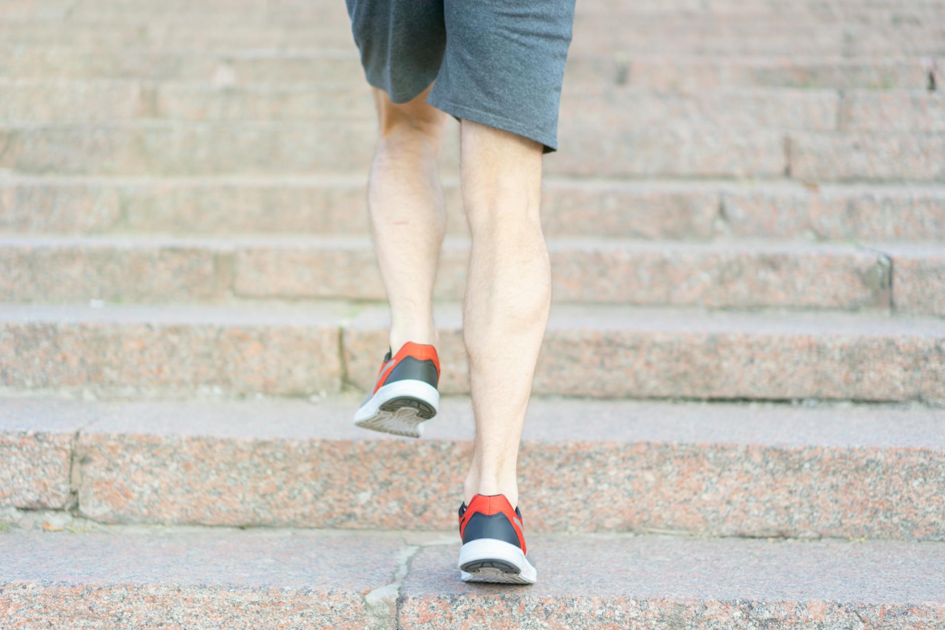 A person in athletic shoes climbing stone steps, showcasing determination and fitness.