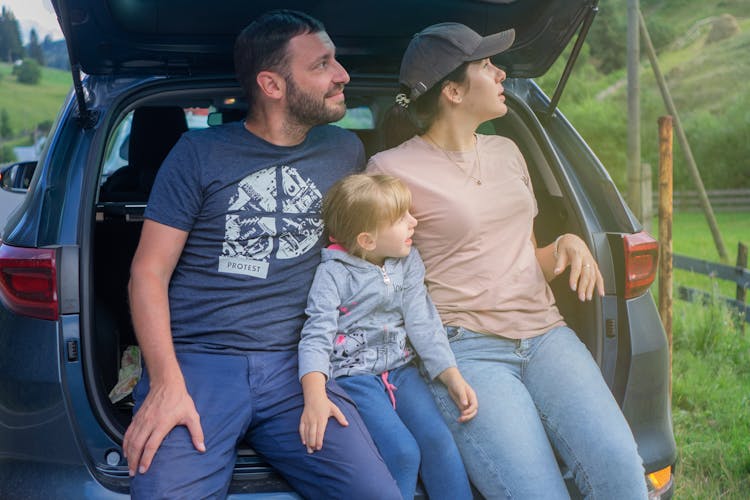 Family Sitting On Car Back