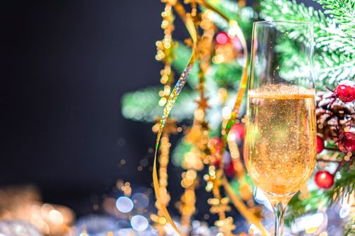 Free Celebrate the festive season with a glass of champagne against a vibrant Christmas tree. Stock Photo