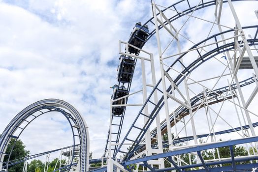 Experience the adrenaline rush of a steel roller coaster under blue skies at an amusement park.