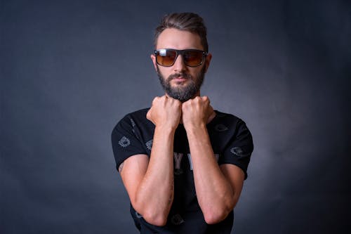 Man Posing in Sports T-Shirt and Sunglasses against Gray Background