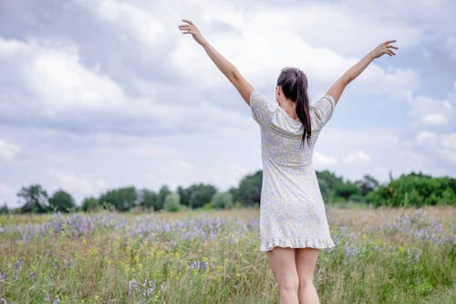 Young Woman with Her Arms Spread on a Field in Summer