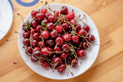 A bowl of juicy red cherries on a wooden table, showcasing freshness and nutrition.