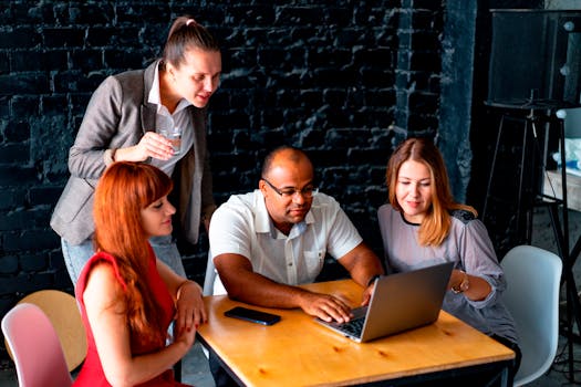 A diverse team of colleagues working together on a laptop in an office.