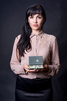 Portrait of a woman holding a miniature house, symbolizing real estate concept.