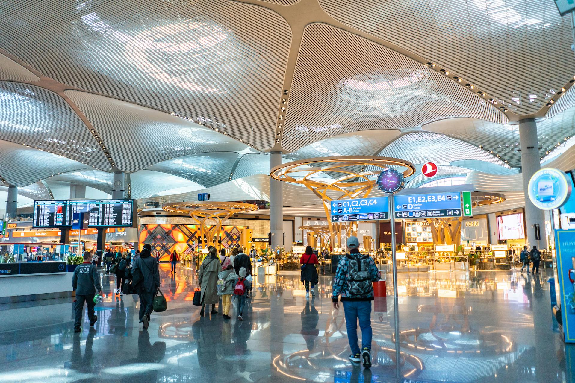 Spacious airport interior with travelers, shops, and architectural details.