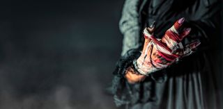 Surreal image of a woman's bloodied, bandaged hand in dark ambiance.