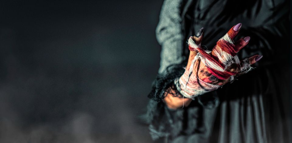 Surreal image of a woman's bloodied, bandaged hand in dark ambiance.