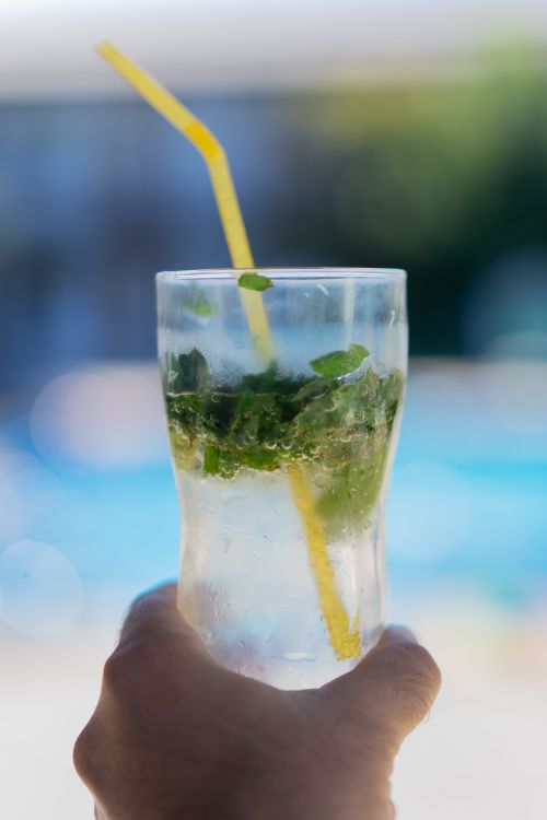 Free A close-up of a cold beverage with mint leaves and a yellow straw, perfect for summer. Stock Photo