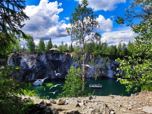 Free Serene lake scene with vibrant trees and rocky cliffs under a bright blue sky. Stock Photo