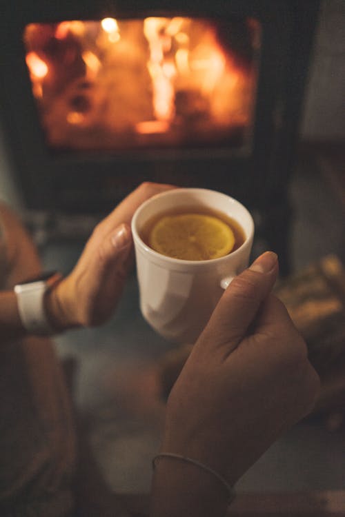 Person Holding White Ceramic Mug With Lemon Tea