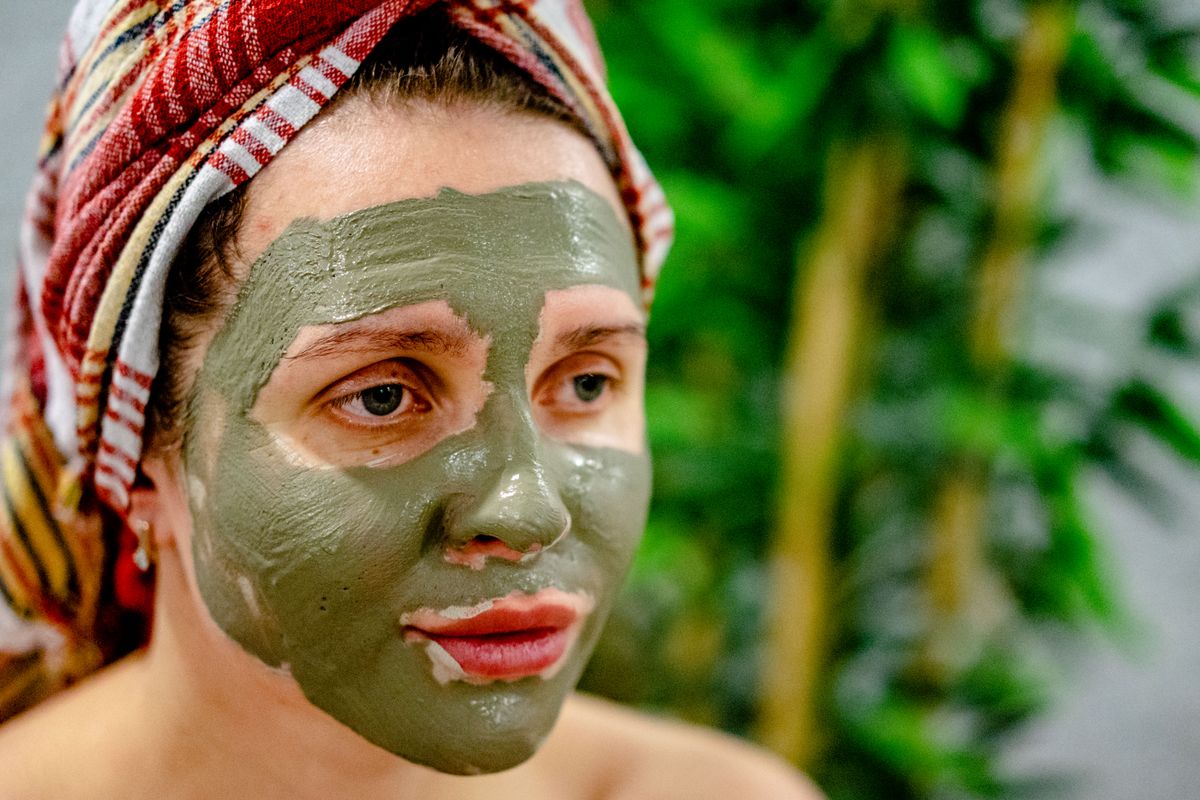 Mujer con mascarilla facial y toalla