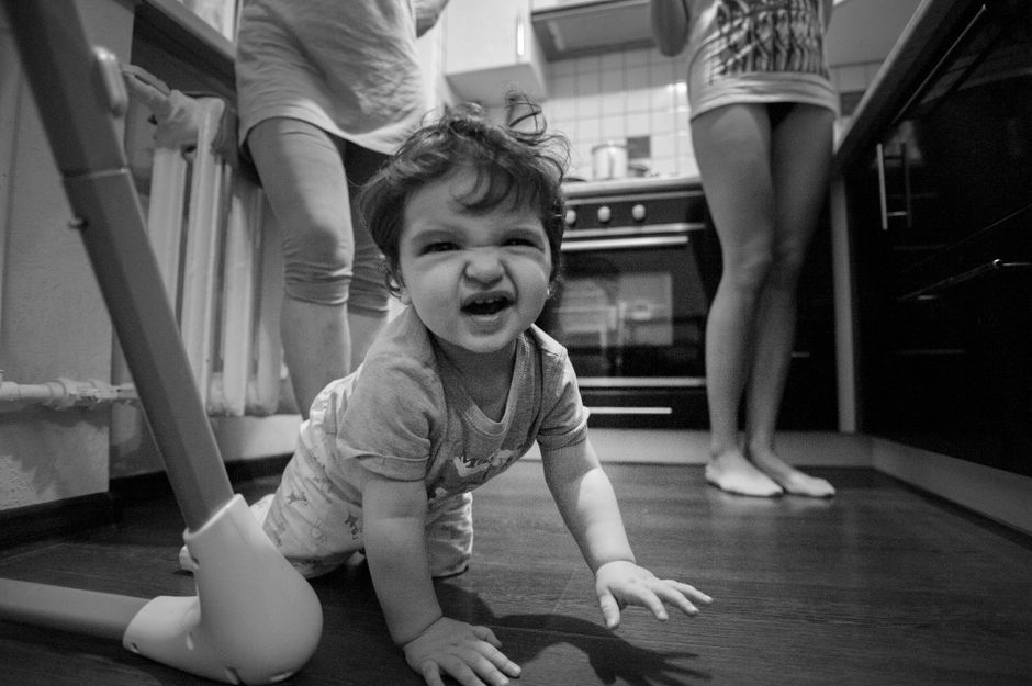 Adorable baby crawling in a monochrome kitchen setting, creating a playful and heartwarming scene.
