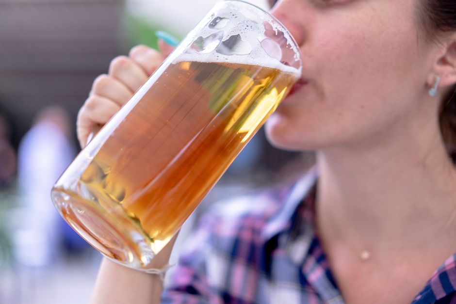 A woman enjoying a lager beer from a clear glass mug. Perfect for lifestyle and beverage-related content.