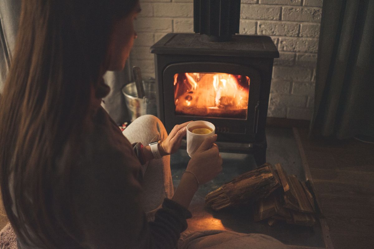 Woman relaxing with tea by the fireplace, prioritizing rest