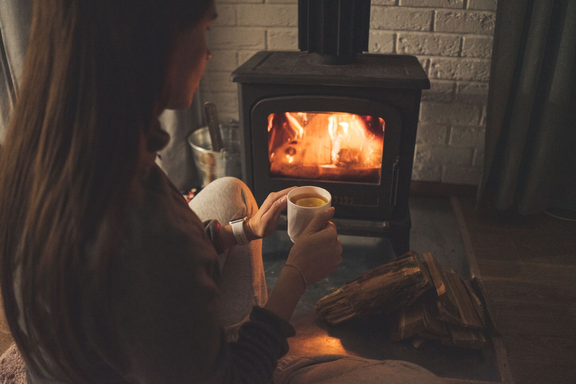 Woman Sitting by the Fireplace with a Cup of Tea