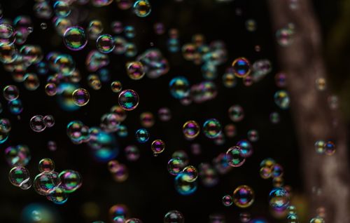 Free Vibrant iridescent soap bubbles floating in the air with a dark backdrop. Stock Photo