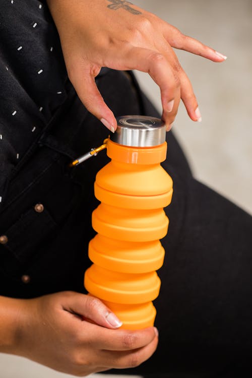 Person Holding Orange and Silver Tumbler