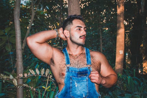 A Man in Denim Jumper Standing Behind Trees