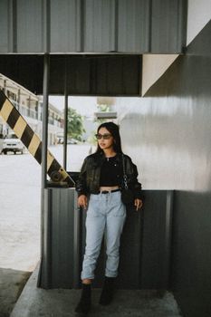 Urban fashion model wearing sunglasses and casual attire in an outdoor city setting. Trendy and modern look.