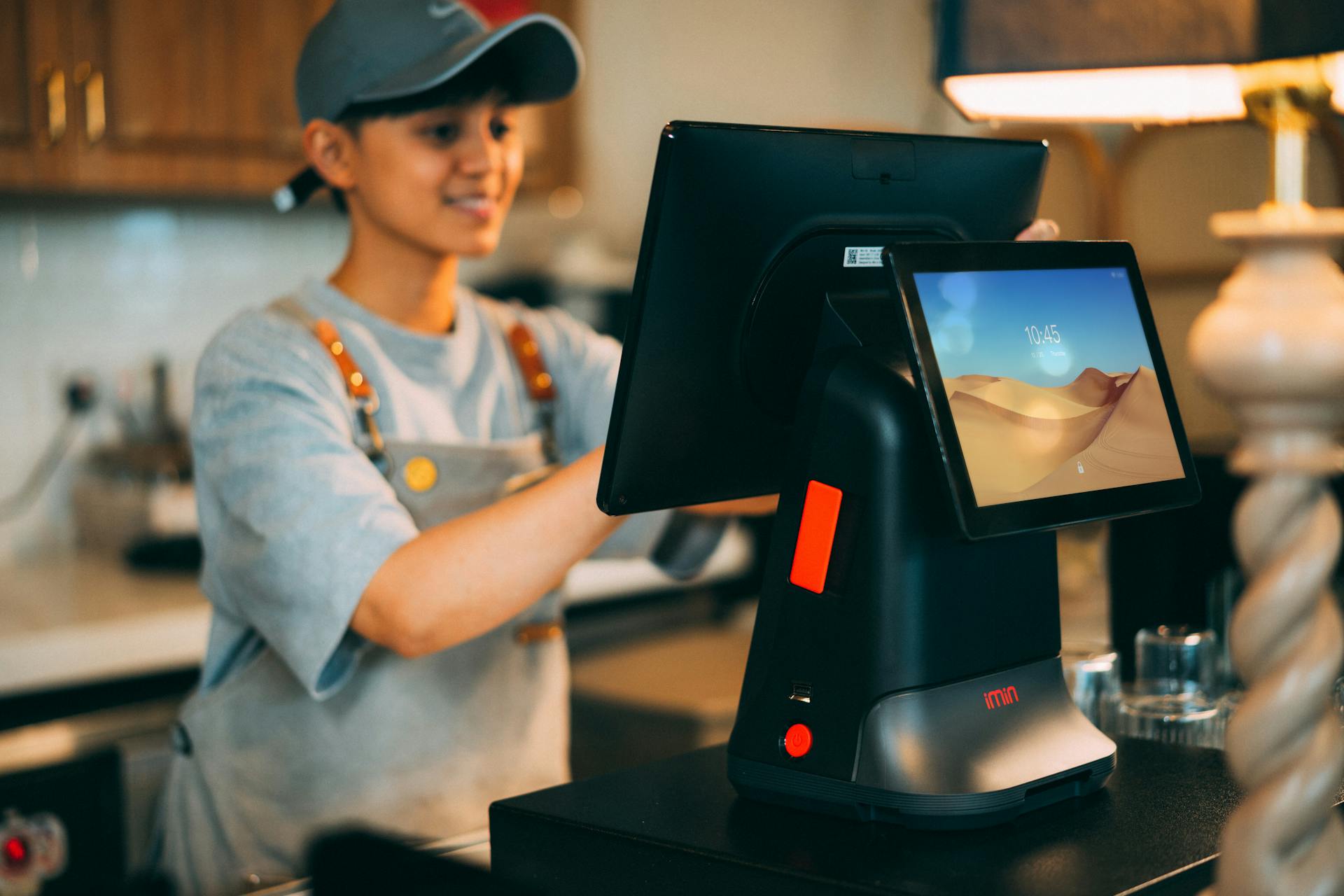 A cashier using a modern point of sale terminal in a store.