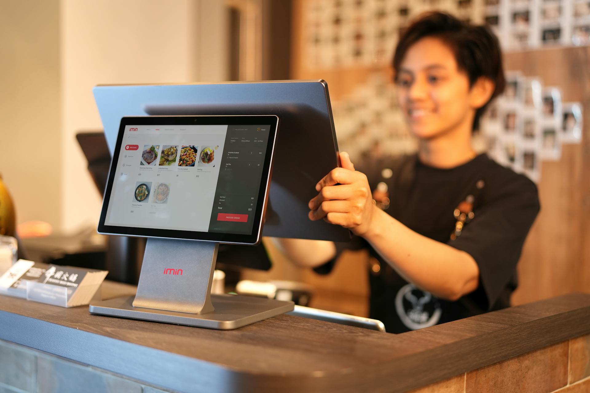 Smiling cashier using a touchscreen POS system in a modern retail environment.