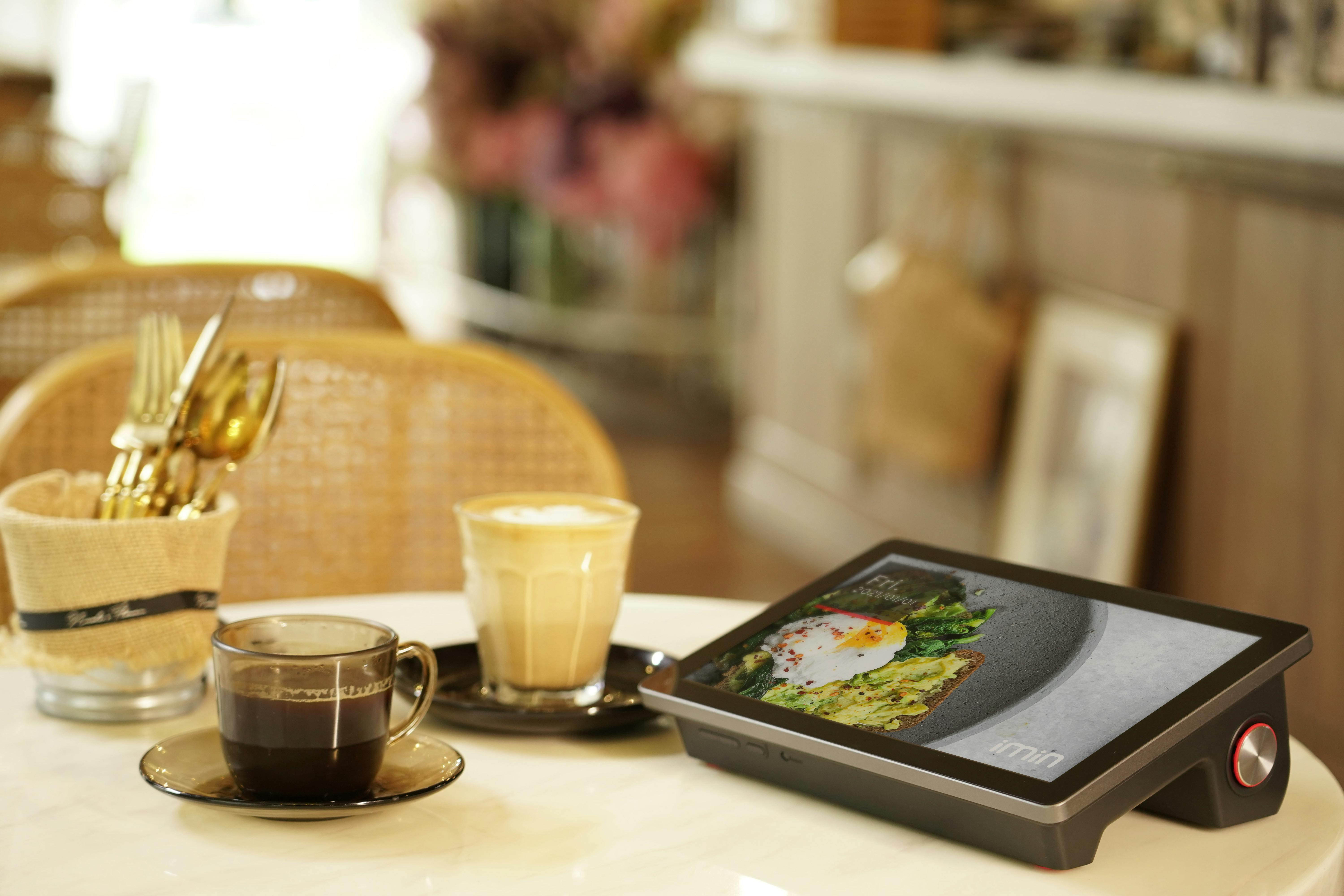 Cozy café setting with coffee cups and a digital menu tablet on the table.